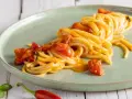 Spaghetti allo scarpariello fumanti, con pomodorini succosi e un tocco piccante, pronti per essere gustati.
