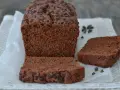 Un soffice plumcake al cioccolato, ricco di gocce, è tagliato a fette su carta da forno.
