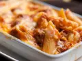 Penne al forno con sugo di pomodoro e mozzarella filante, un classico della pasta alla sorrentina.