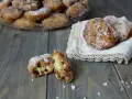 Frittelle di riso ricetta della nonna: dolcetti dorati e zuccherati, uno aperto rivela l'interno soffice e i chicchi d'uva passa.
