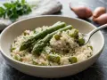 Un cremoso risotto con asparagi freschi, guarnito con prezzemolo tritato. Una forchettata mostra la consistenza perfetta.