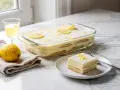Un delizioso tiramisù al limone, con savoiardi e crema, guarnito con scorza di limone e fette.