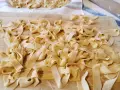 Fettuccine fresche, tagliatelle fatte in casa sparse su un tagliere di legno, pronte per essere cucinate.