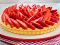 Una deliziosa crostata di fragole, con una base dorata e un ripieno cremoso, ricoperta da fragole fresche affettate.