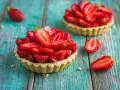Deliziosi dolci con fragole fresche, disposti su un tavolo di legno turchese.