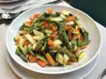 Un piatto invitante di verdure in padella: carote, zucchine e asparagi tagliati a pezzetti, cotti al punto giusto.