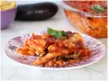 Piatto di pasta alla siciliana con melanzane, pomodoro e basilico, appena sfornata.
