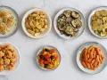Sette piatti di verdure in friggitrice ad aria: finocchi gratinati, patate arrosto, melanzane, zucchine, cavolfiore fritto, peperoni e carote.