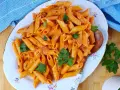 Piatto di penne al baffo cremose, guarnite con prezzemolo fresco, pronte per essere gustate.