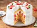 Torta panna e fragole, soffice e invitante, con strati di pan di Spagna, panna montata e fragole fresche, decorata con fragole a fette e ciuffi di panna.