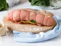 Un arrosto al forno pronto per essere cucinato, legato con spago, su un tagliere con sale grosso e verdure.
