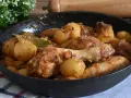 Un saporito pollo in umido con patate e alloro, cotto in una padella di ghisa, pronto per essere gustato.
