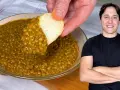 Un uomo sorride mentre un pezzo di pane intinge in una ciotola di saporite lenticchie in umido.