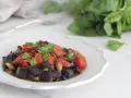 Un piatto invitante di melanzane a funghetto con pomodorini e basilico fresco, pronto per essere gustato.