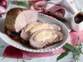 Arrosto di vitello morbido con sughetto benedetta, servito su un piatto bianco con cipolle rosse e rosmarino.