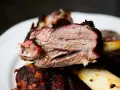 Succulento stinco di maiale affumicato, cotto lentamente fino a diventare tenerissimo. La carne rosa e succosa si stacca dall'osso.