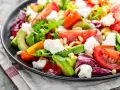 Insalata fresca con pomodori, lattuga, formaggio e avocado a fette, guarnita con pinoli.