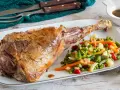 Succulento agnello al forno, dorato e profumato, servito con un contorno di verdure miste colorate.