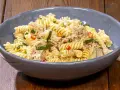 Fusilli con zucchine, tonno e peperoncino in una ciotola blu su un tavolo di legno. Un piatto semplice e gustoso.