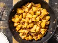 Patate in tecia dorate e croccanti, con pezzetti di pancetta e cipolla, pronte per essere gustate.