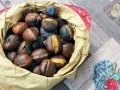 Castagne in friggitrice ad aria, pronte per essere gustate. Un sacchetto di carta marrone trabocca di castagne calde e dorate, alcune con tagli che rivelano il loro interno morbido.
