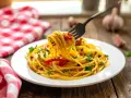 Un piatto di spaghetti alla carrettiera fumante, conditi con pomodoro, aglio e prezzemolo, pronti per essere gustati.