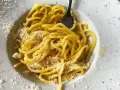 Un piatto di pasta in bianco, spaghetti conditi con formaggio grattugiato e un filo d'olio, pronti per essere gustati.