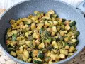 Zucchine gratinate in padella, dorate e saporite, con un rametto di rosmarino fresco.