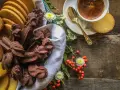 Cesto pieno di biscotti fatti in casa al cioccolato e alla vaniglia, accanto a una tazzina di caffè e bacche rosse.