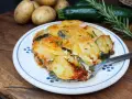 Piatto invitante di patate e zucchine al forno, dorate e filanti, con rosmarino fresco. Un contorno perfetto per ogni pasto.