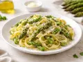 Un piatto invitante di pasta con asparagi freschi, condita con parmigiano grattugiato e prezzemolo.