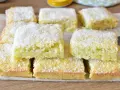 Fette di torta al cocco, soffici e dorate, cosparse di scaglie bianche. Un dolce profumato e invitante.