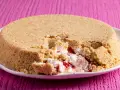 Cheesecake con yogurt greco e marmellata di fragole, con una crosta friabile di biscotti. Un morso goloso rivela il ripieno cremoso.