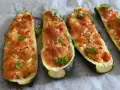 Zucchine tonde ripiene al forno, dorate e filanti, guarnite con foglie di menta fresca.