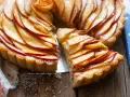 Una fetta di crostata di mele lucida e dorata, con le mele disposte a spirale su una base friabile.