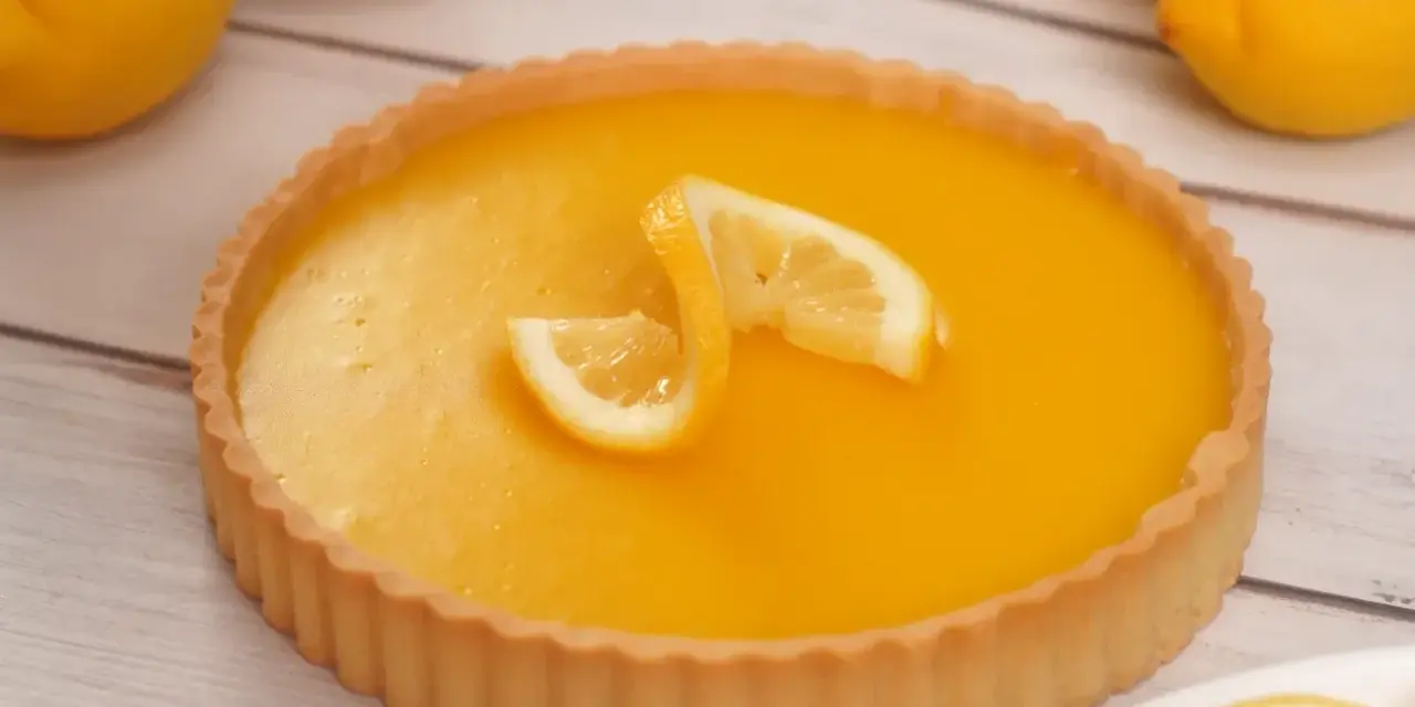 Una deliziosa crostata al limone, con la sua crema gialla brillante e decorata con spicchi di limone fresco.
