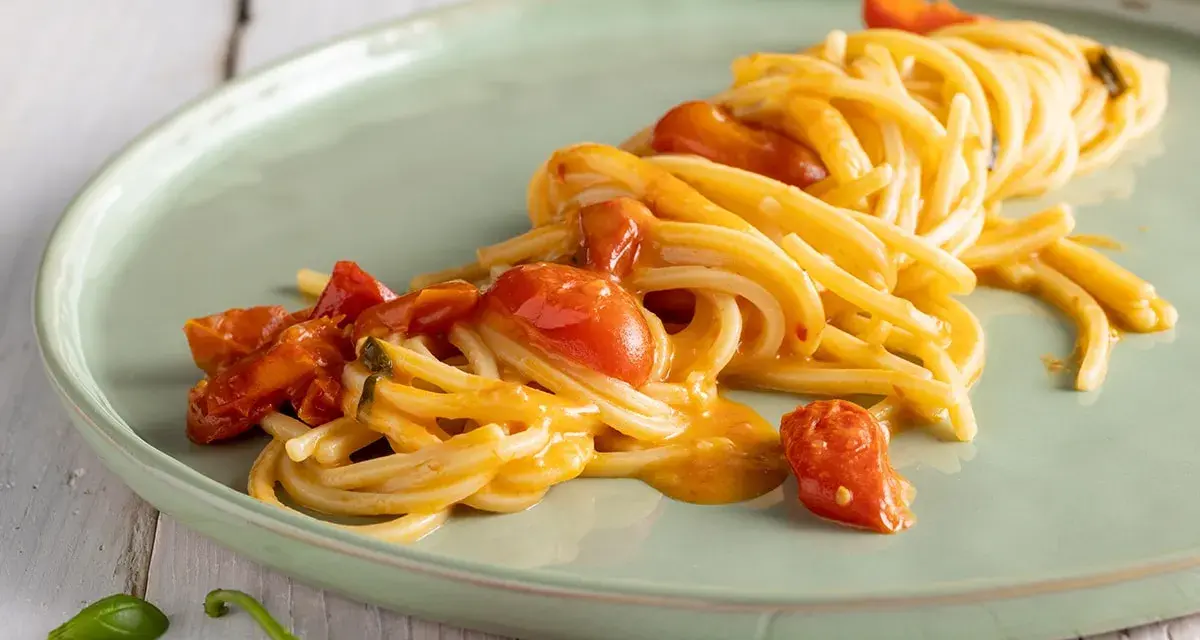 Spaghetti allo scarpariello fumanti, con pomodorini succosi e un tocco piccante, pronti per essere gustati.