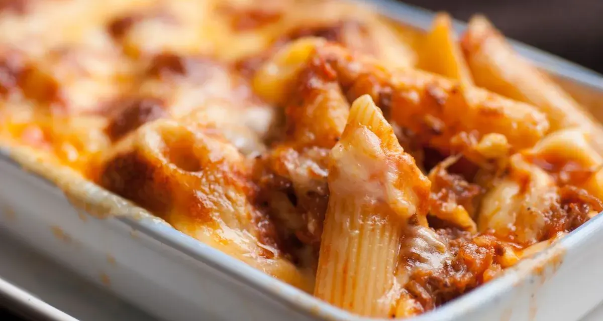 Penne al forno con sugo di pomodoro e mozzarella filante, un classico della pasta alla sorrentina.