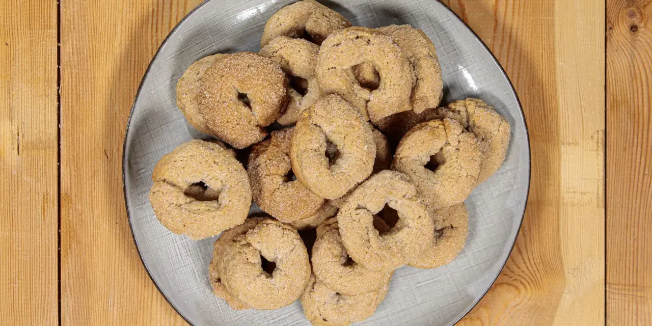 Piatto di ciambelline al vino, dolcetti friabili e dorati, perfetti per accompagnare un caffè o un tè.