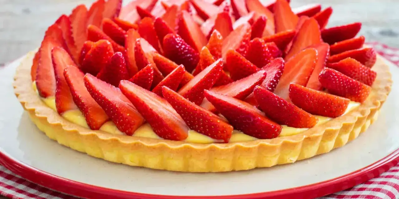 Una deliziosa crostata di fragole, con una base dorata e un ripieno cremoso, ricoperta da fragole fresche affettate.