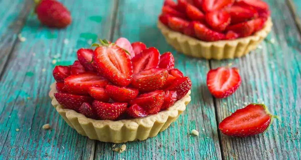 Deliziosi dolci con fragole fresche, disposti su un tavolo di legno turchese.