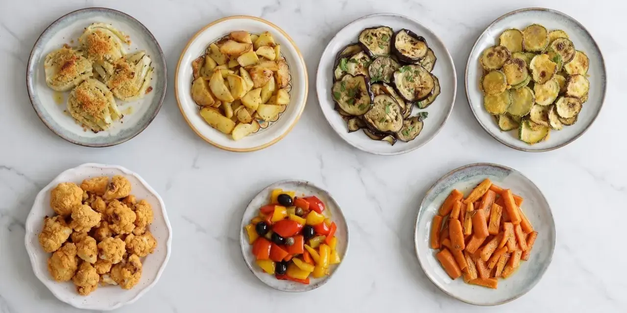 Sette piatti di verdure in friggitrice ad aria: finocchi gratinati, patate arrosto, melanzane, zucchine, cavolfiore fritto, peperoni e carote.