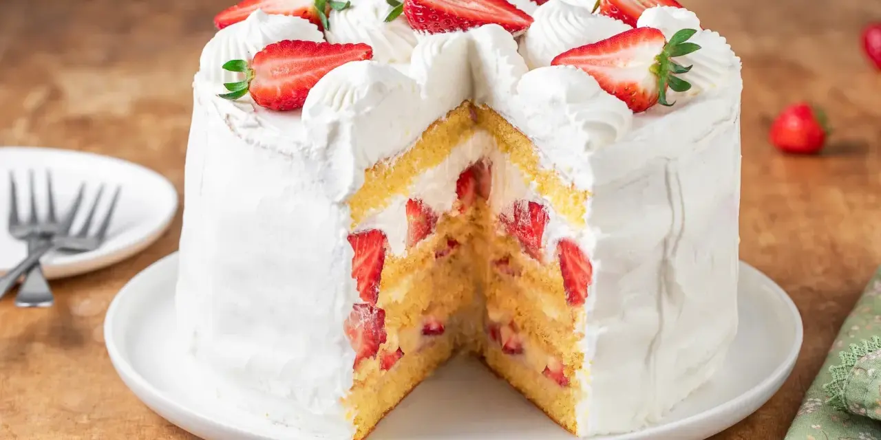 Torta panna e fragole, soffice e invitante, con strati di pan di Spagna, panna montata e fragole fresche, decorata con fragole a fette e ciuffi di panna.
