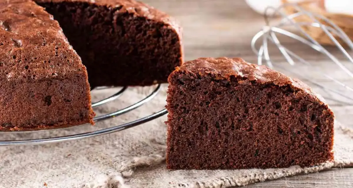 Una fetta di torta al cioccolato soffice e invitante, appena sfornata, su un tavolo di legno.