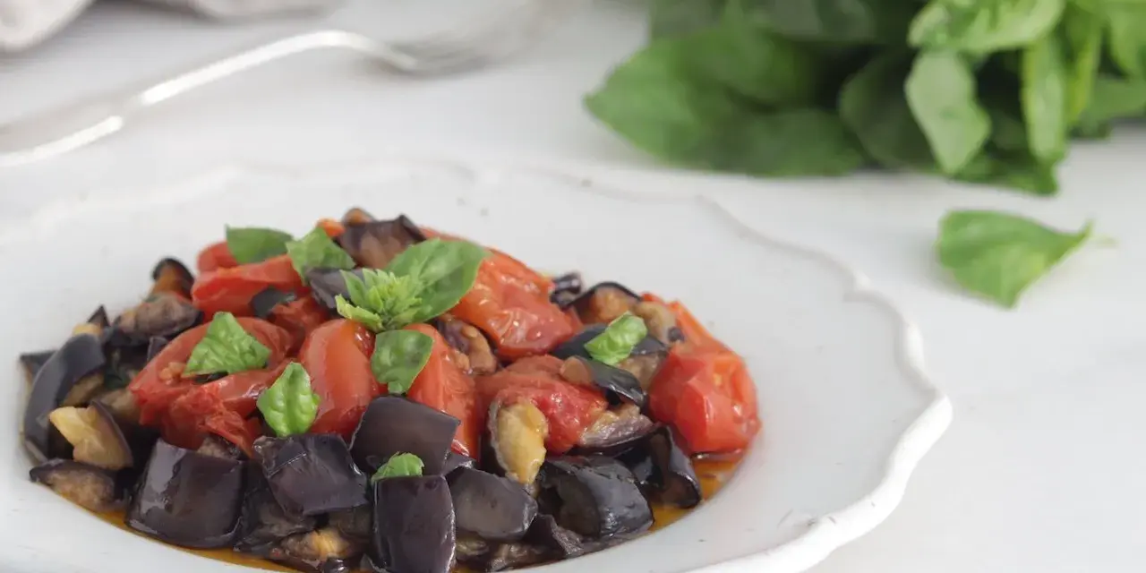 Un piatto invitante di melanzane a funghetto con pomodorini e basilico fresco, pronto per essere gustato.