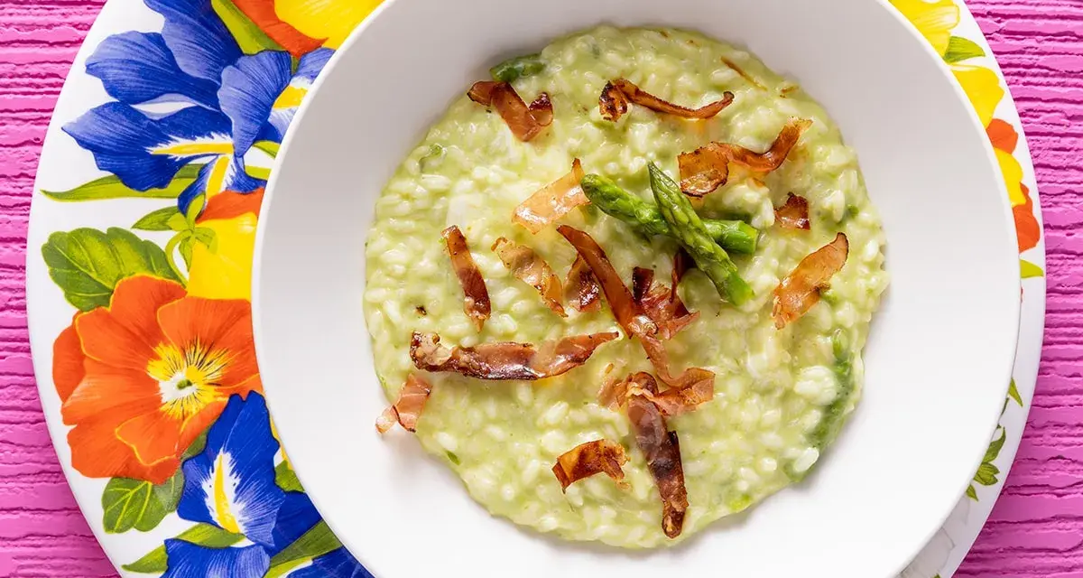 Un cremoso risotto asparagi e speck, guarnito con punte di asparagi freschi e croccanti listarelle di speck.