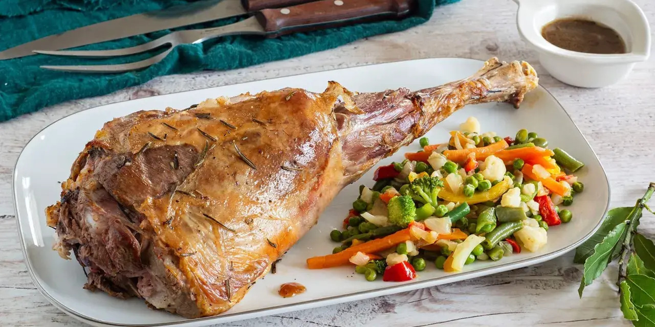 Succulento agnello al forno, dorato e profumato, servito con un contorno di verdure miste colorate.