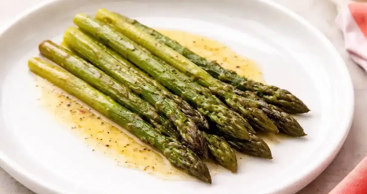 Asparagi in padella, cotti alla perfezione e conditi con un leggero sughetto.