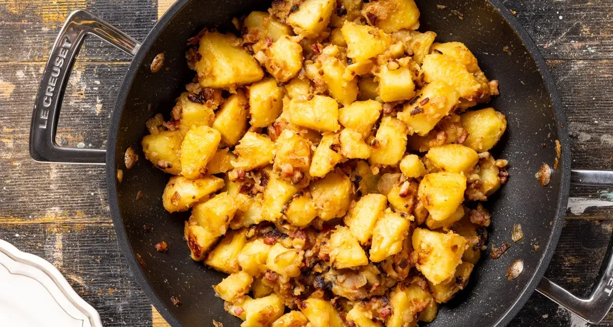 Patate in tecia dorate e croccanti, con pezzetti di pancetta e cipolla, pronte per essere gustate.