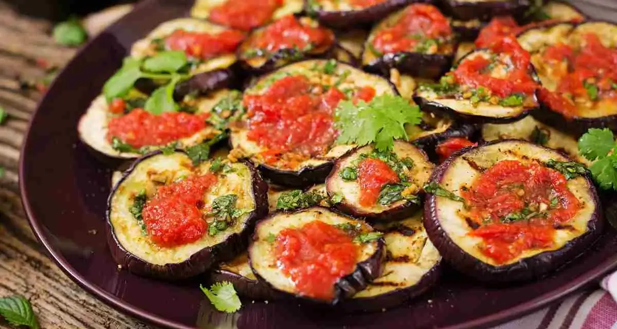 Fette di melanzane grigliate condite con salsa di pomodoro e basilico, un piatto invitante di melanzane alla pizzaiola.